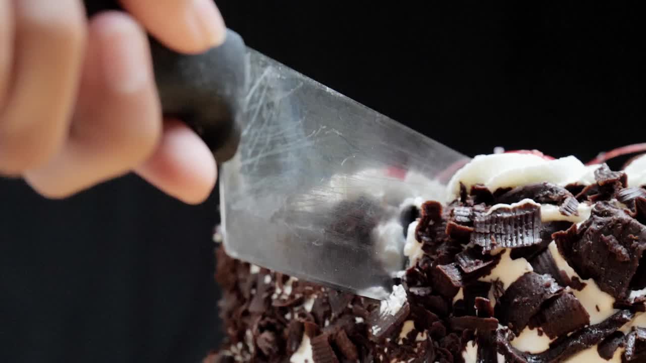 用慢镜头切割黑色背景的巧克力蛋糕。视频下载