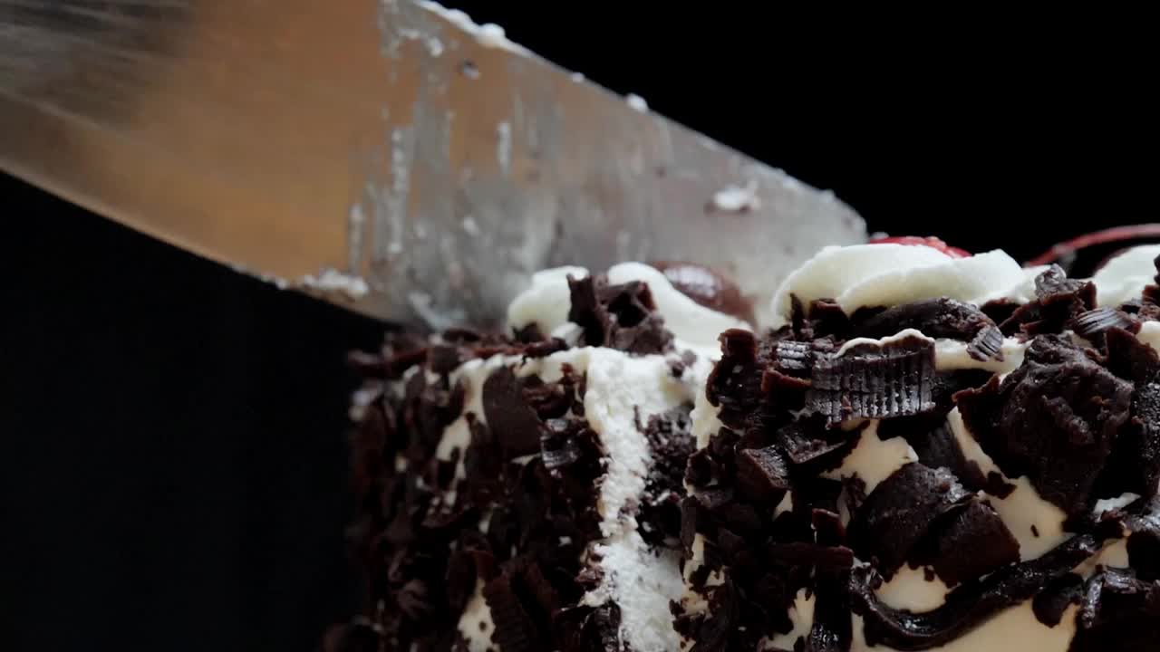 用慢镜头切割黑色背景的巧克力蛋糕。视频下载