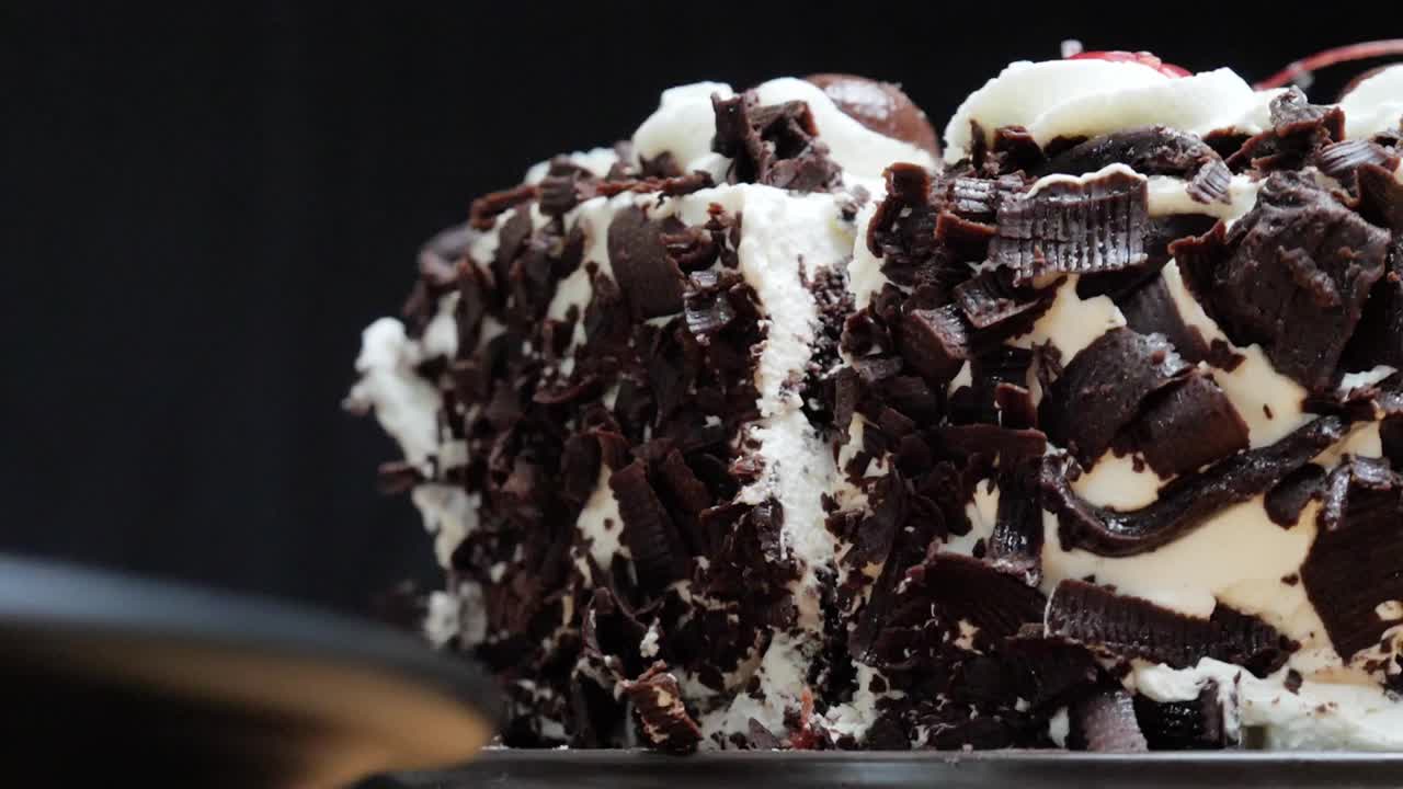 在黑色的背景上吃一块黑巧克力蛋糕，慢镜头。视频下载