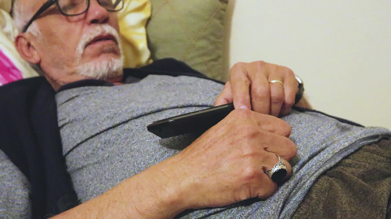老人看电视时拿着遥控器睡着了视频素材