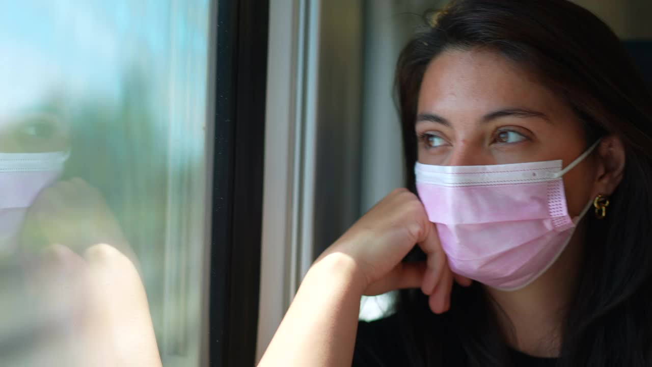 列车乘客戴着新冠肺炎口罩。带着医用口罩乘坐交通工具的女人视频下载