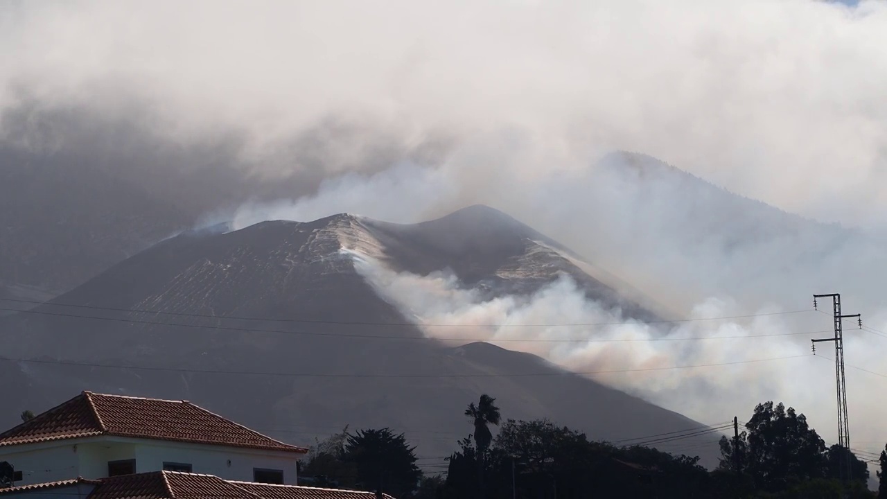 一座城镇房屋旁边的火山爆发。在多斯皮诺斯镇的房子旁边，可以看到烟雾和熔岩柱状的康伯利维亚火山。视频下载