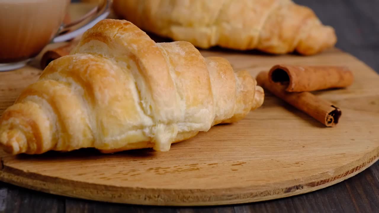 新鲜开胃的羊角面包和咖啡，木质背景，美味的早餐理念视频下载