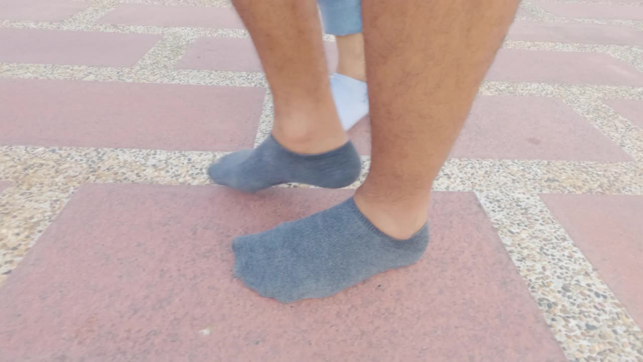 一对穿着袜子的夫妇的腿走在人行道上。视频下载