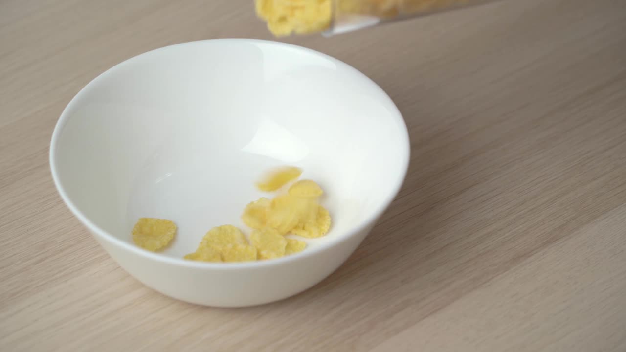 白色盘子里掉落的玉米片的慢动作特写。视频素材