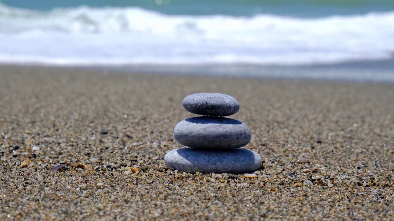 海滩上的岩石保持平衡。沙滩上的卵石金字塔。稳定堆或软焦堆散景，近距离。禅宗的平衡，极简主义，和谐与和平视频素材