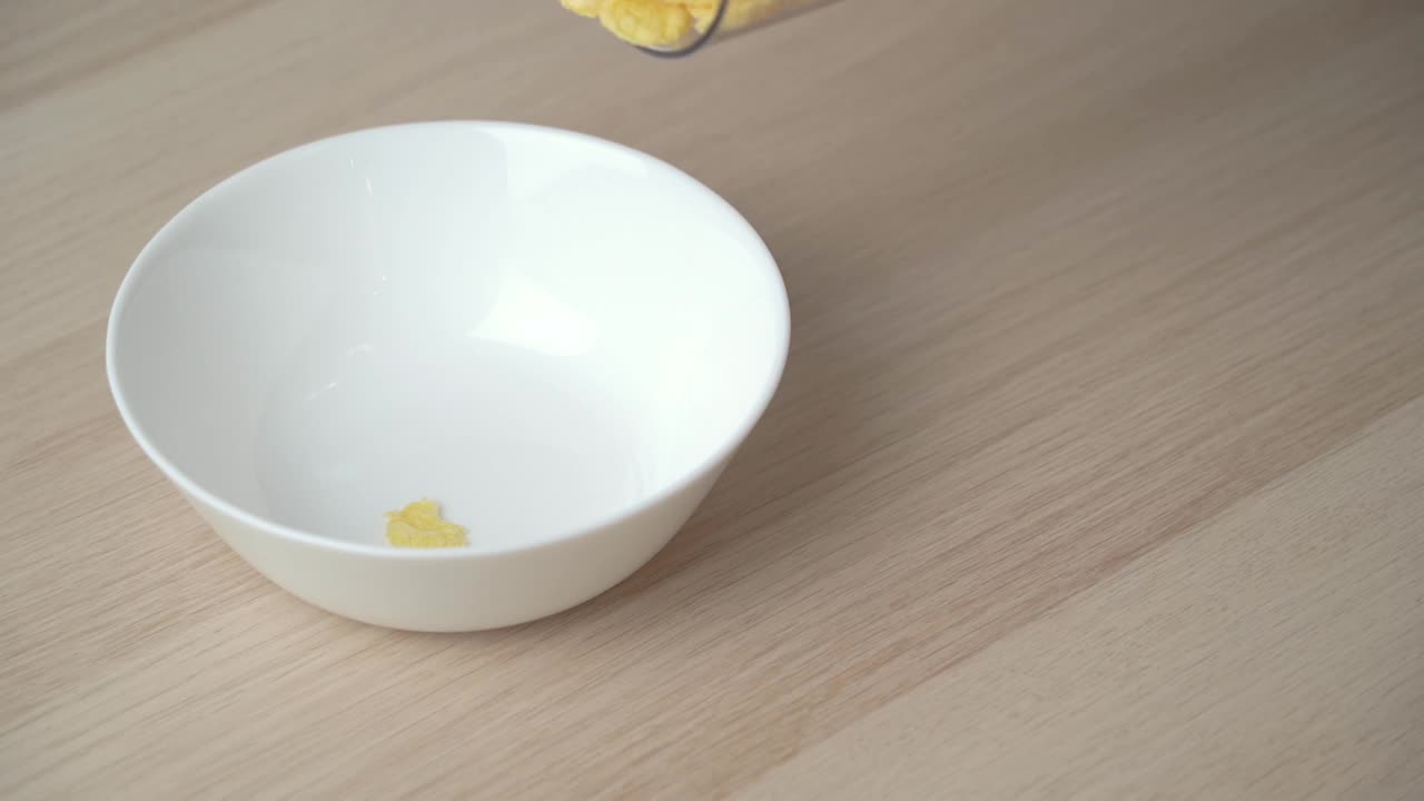 白色盘子里掉落的玉米片的慢动作特写。视频素材