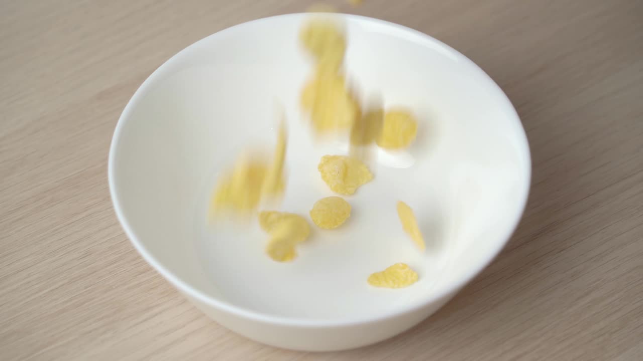 把玉米片倒进白色盘子里的慢镜头拉近。视频素材