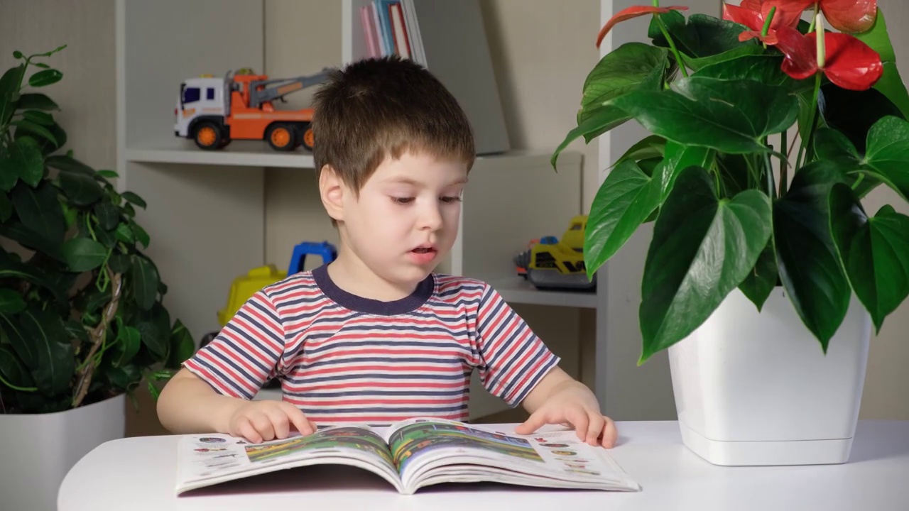 一个穿着条纹t恤的孩子学习阅读，看着图画书并说话。视频素材