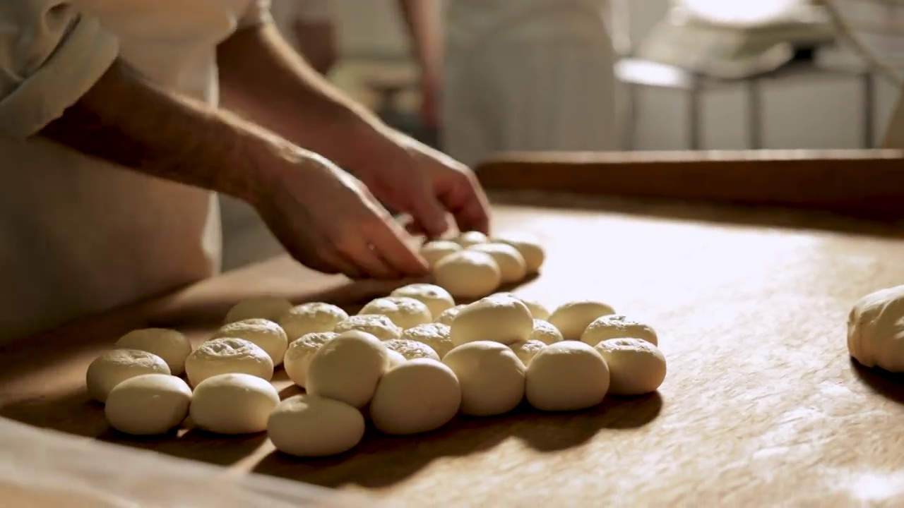 在面包房，熟练的面包师在做小圆面包视频素材