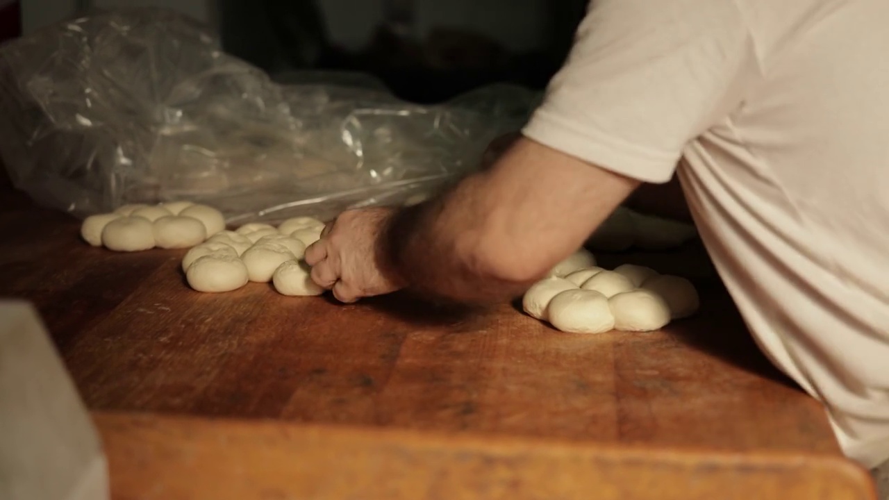 在面包房的厨房里，面包师在做小圆面包视频素材