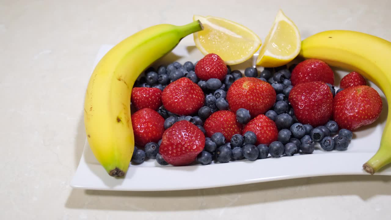 水果沙拉什锦水果。新鲜草莓、蓝莓、香蕉、柠檬。热带健康的混合。维生素。视频素材
