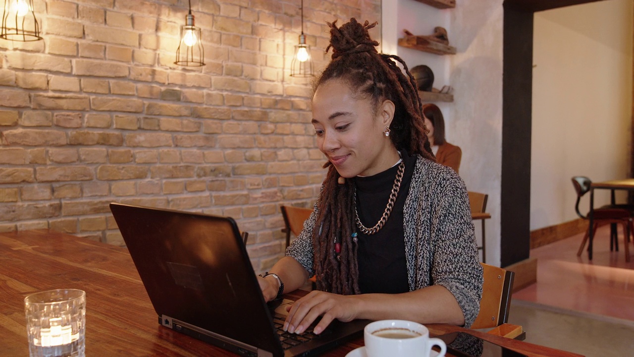 美丽的女人坐在咖啡厅，在笔记本电脑上工作视频下载