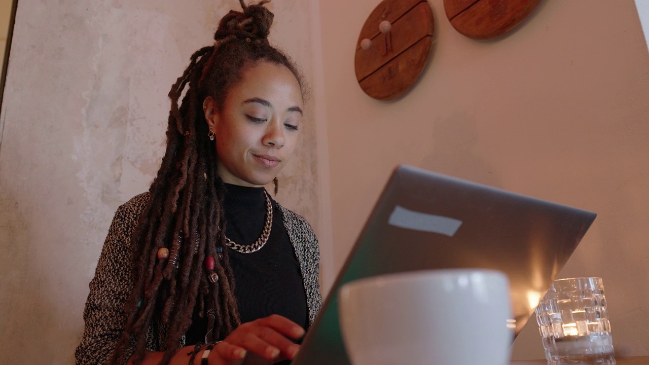 年轻女性自由职业者在wifi咖啡厅用笔记本电脑视频下载