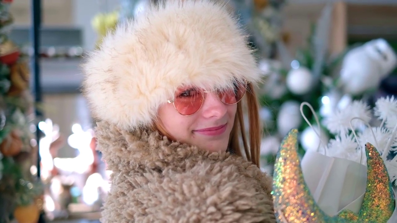 年轻迷人的女孩在帽子使圣诞节购物视频购买