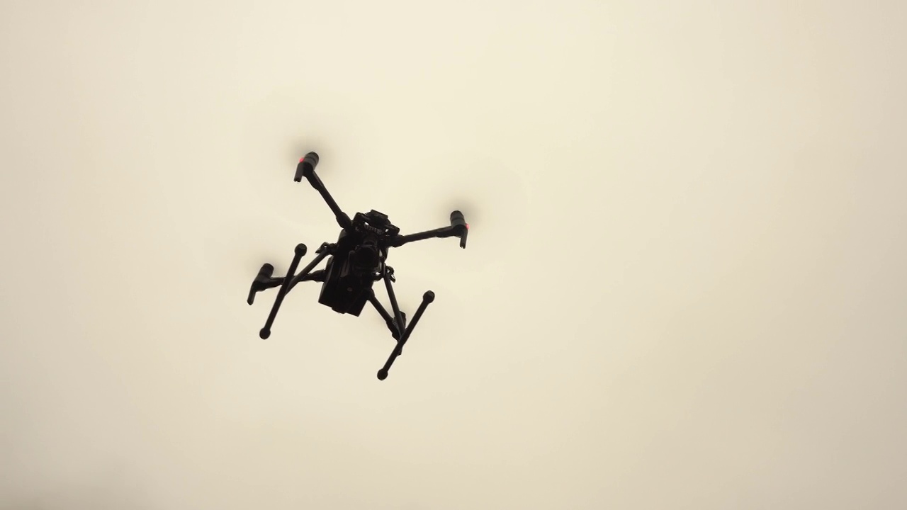 一架带着摄像机的无人直升机盘旋在空中。现代军用无人机。视频下载