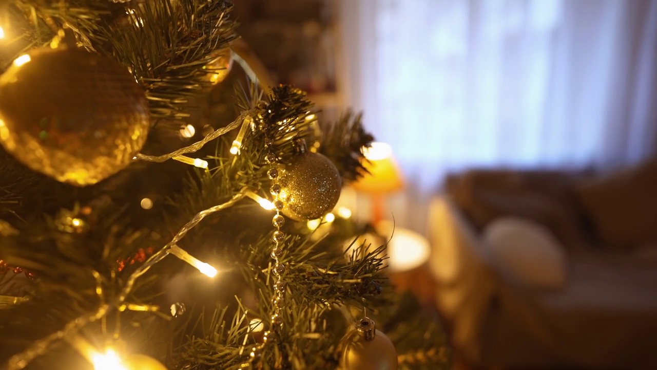 近景慢动作美丽的微笑的女人装饰圣诞树在家里的灯泡。在家里布置节日气氛，庆祝圣诞节和新年视频素材