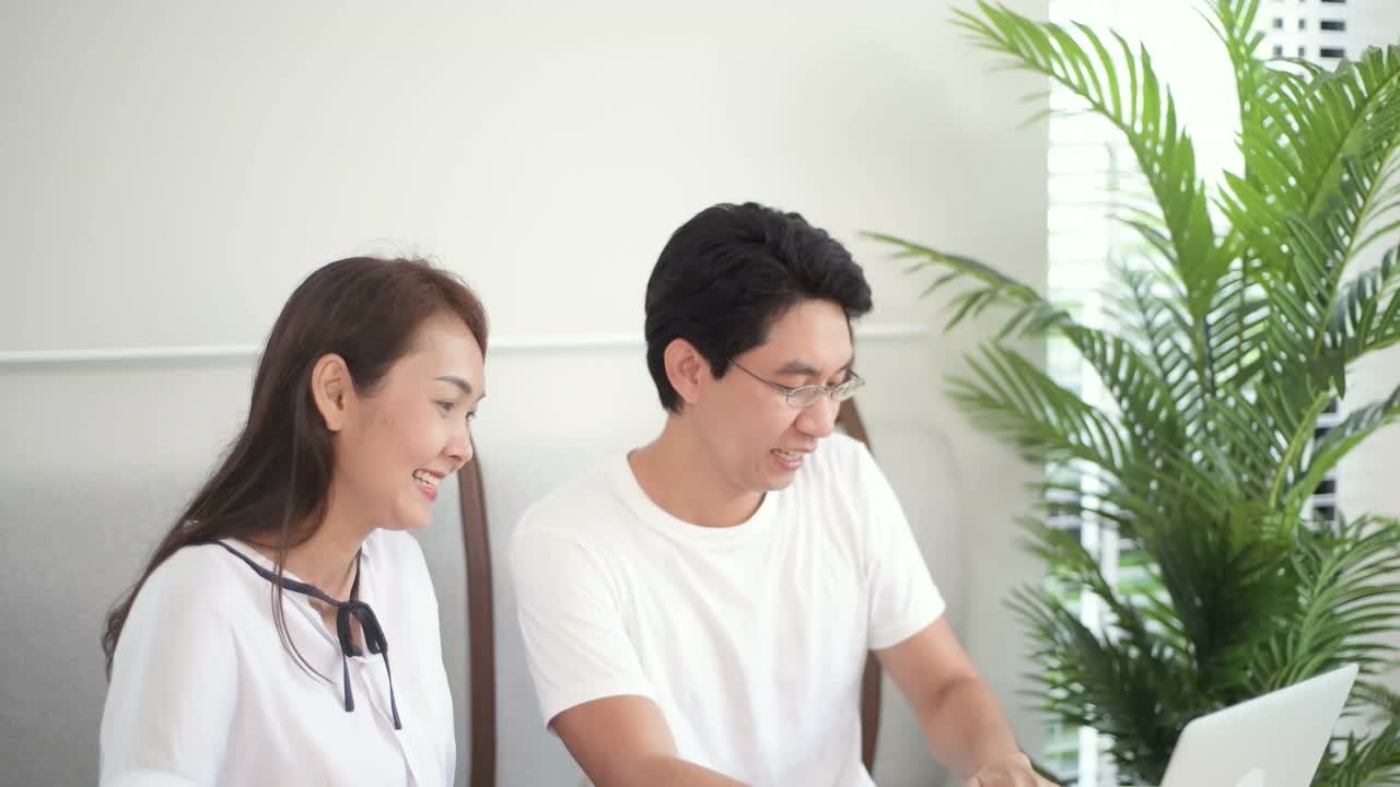 兴奋的亚洲夫妇使用笔记本电脑，获奖者视频素材