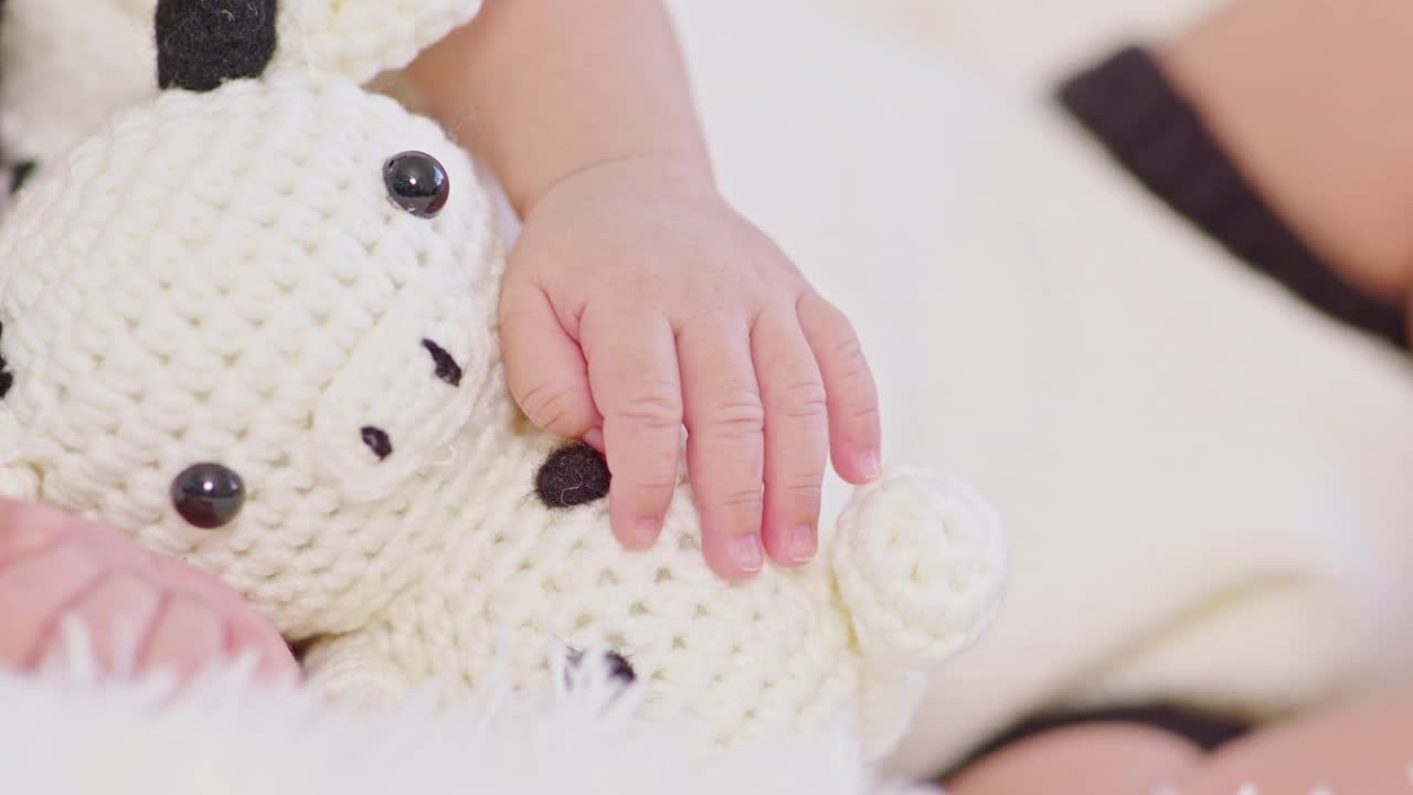 亲密的手快乐的新生婴儿穿着可爱的奶牛服装躺着睡觉拥抱奶牛娃娃在白色的背景舒适和安全。可爱的亚洲婴儿在婴儿床上睡觉和打盹视频素材