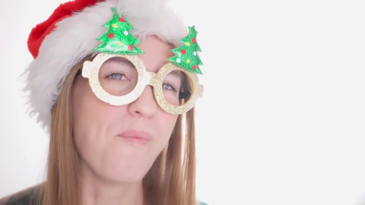 戴眼镜戴圣诞树的有趣女孩。戴着圣诞老人帽子的漂亮女人视频素材