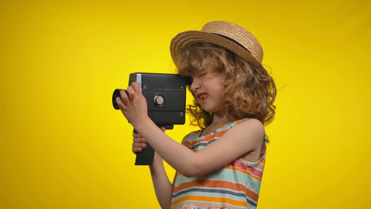 戴草帽的女摄影师用黄色背景的复古摄像机拍摄视频下载