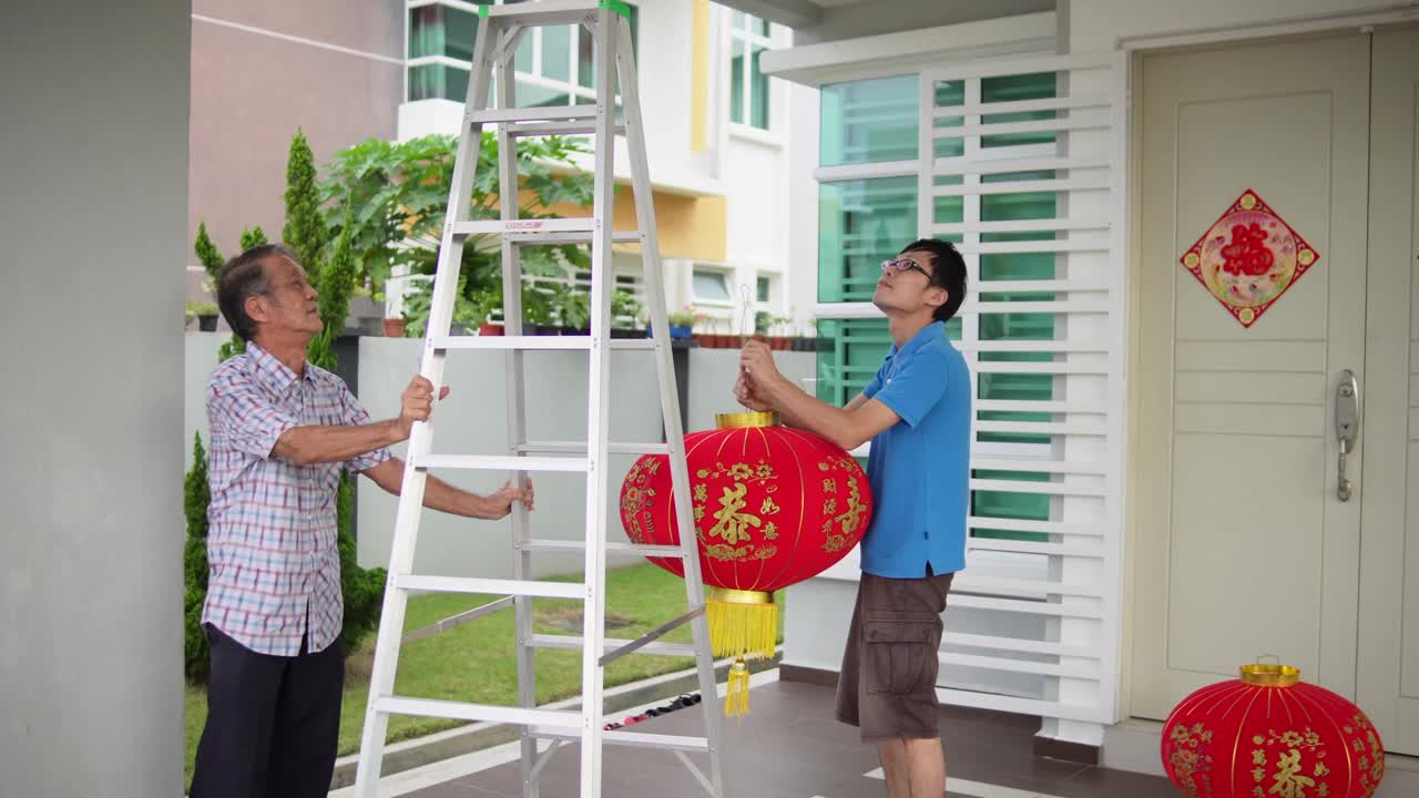 亚洲华人父亲在除夕夜在他们家的前院给儿子递红灯笼视频下载