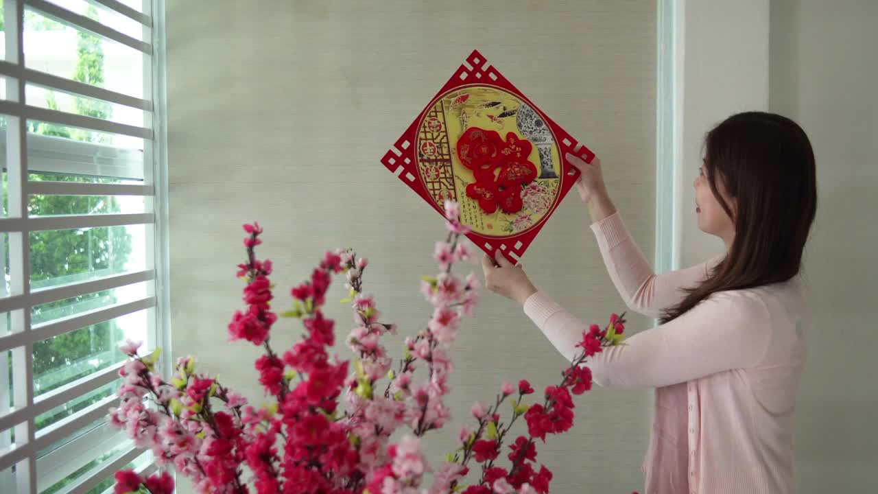 亚洲的中国妇女在中国新年前夕用“财运”春联装饰她的房子视频下载