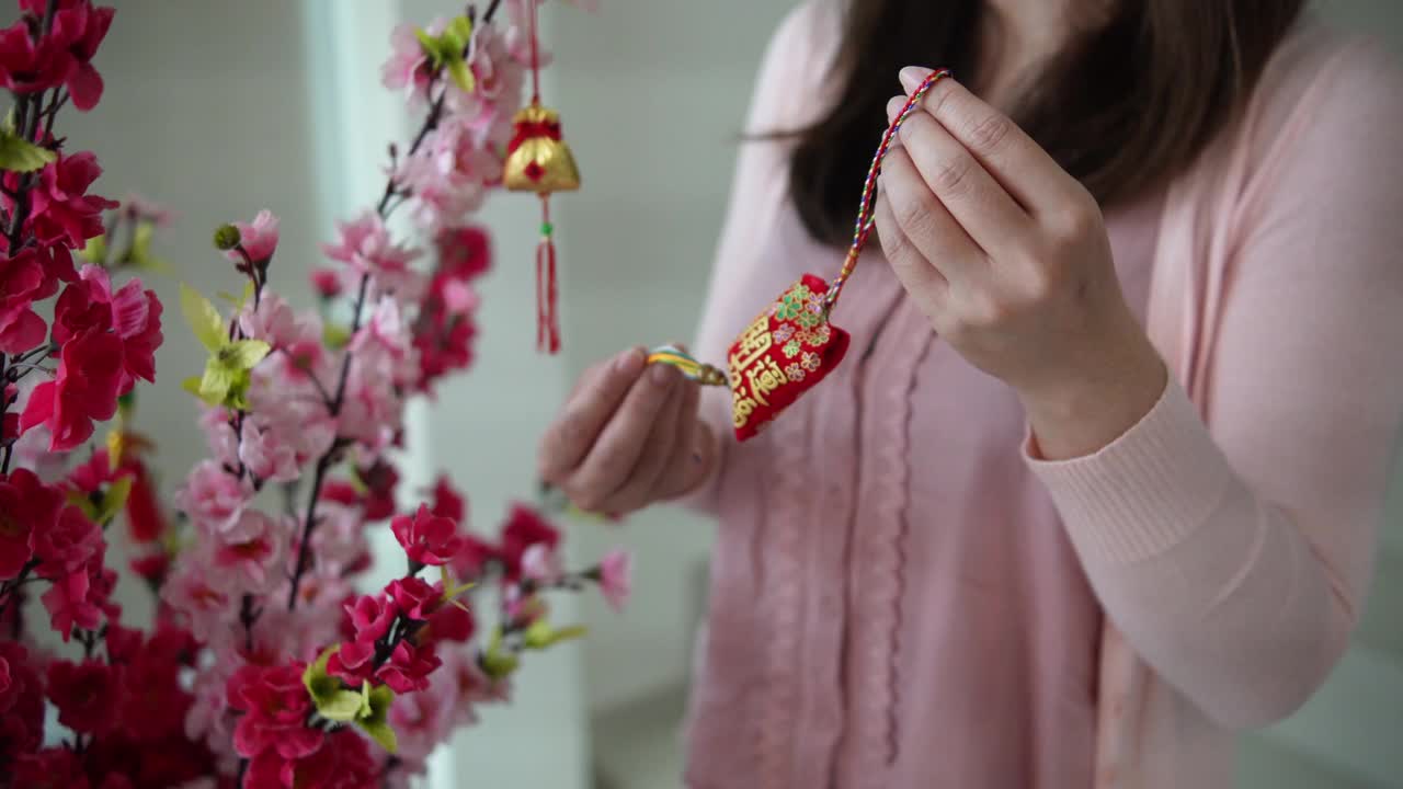 亚洲华人微笑的妇女在樱花上装饰中国新年的装饰品视频下载