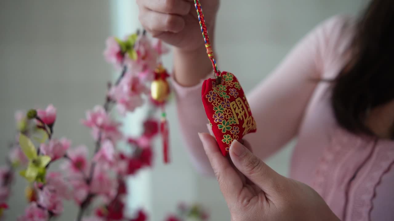 亚洲华人微笑的妇女在樱花上装饰中国新年的装饰品视频下载
