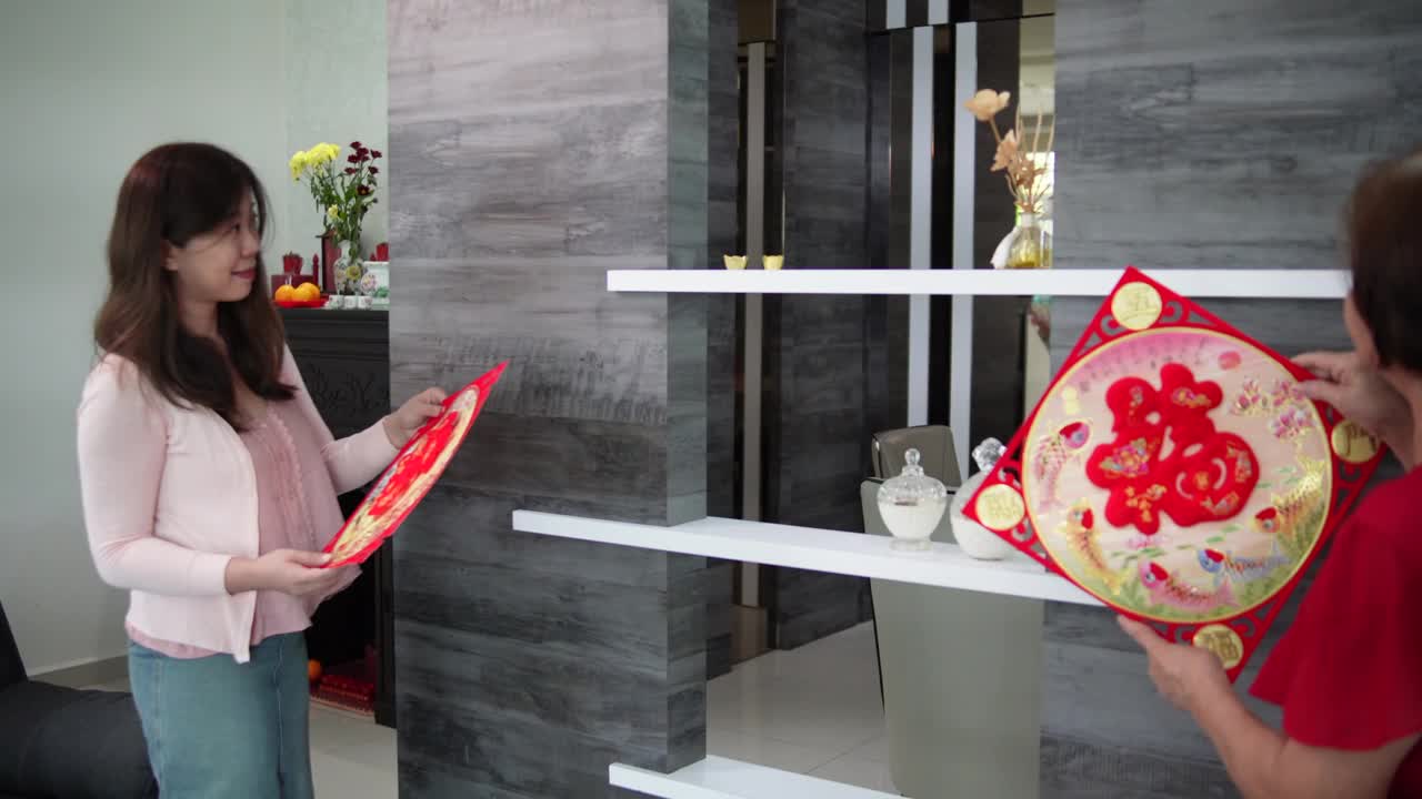 亚洲华人妇女和母亲在中国新年前夕用“财运”春联装饰她的客厅视频素材
