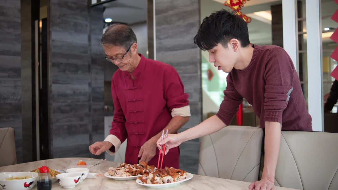 在中国新年期间，亚洲的中国年轻人和他的父亲在餐桌上准备食物视频素材