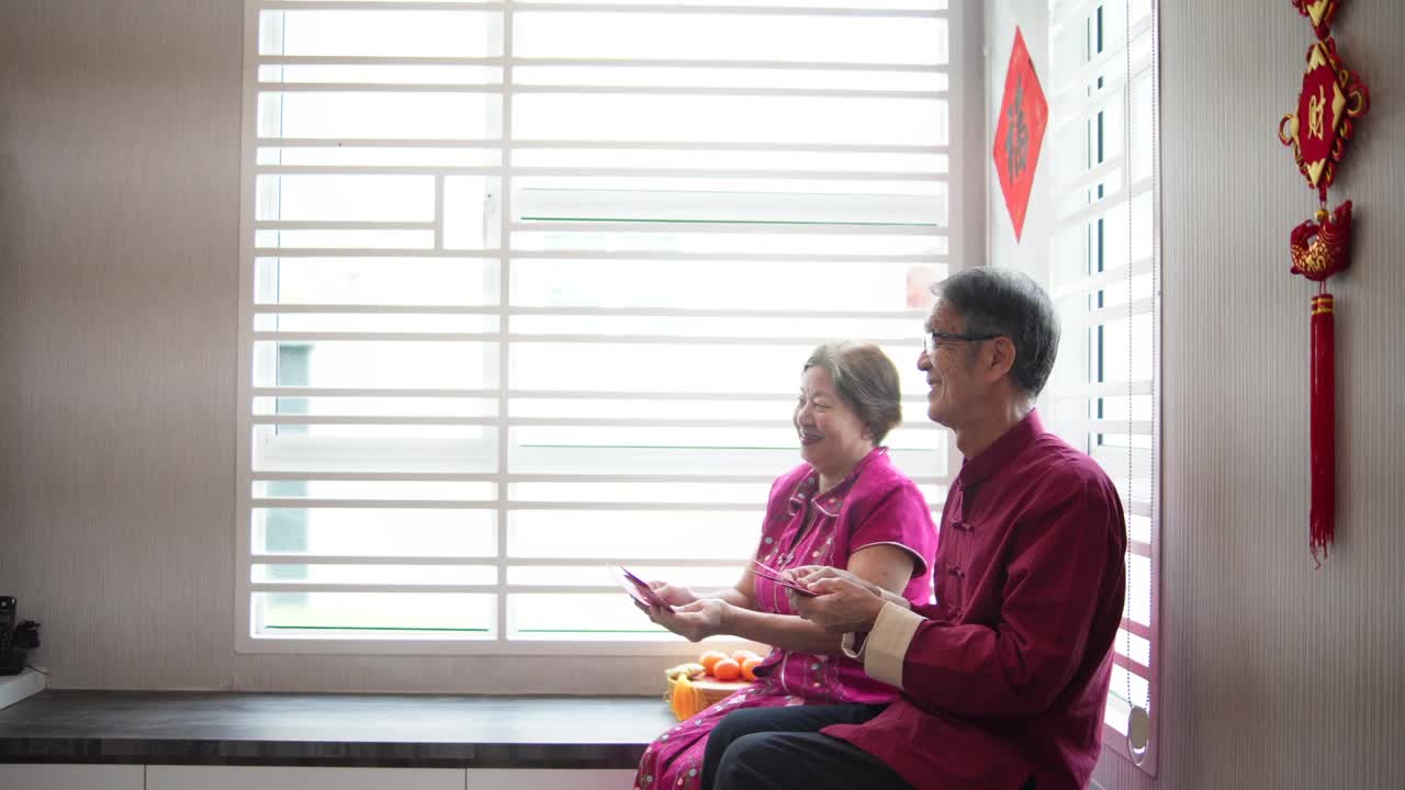 亚洲华人老人微笑着给他们的孩子红包在生活大厅中国新年视频下载
