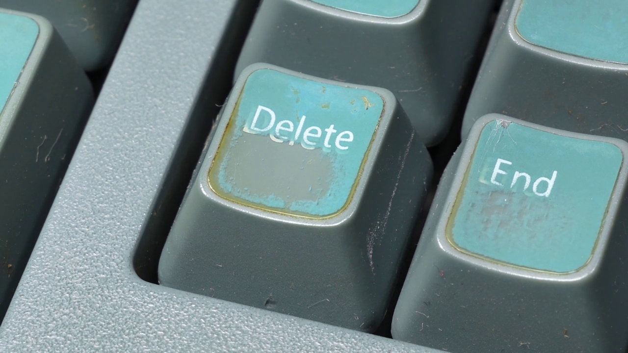 手指用力按下删除键，按下删除键在一个旧的褪色旧的复古桌面PC键盘上，高角度，细节，宏，极端特写删除用户文件，数字数据删除过程视频下载
