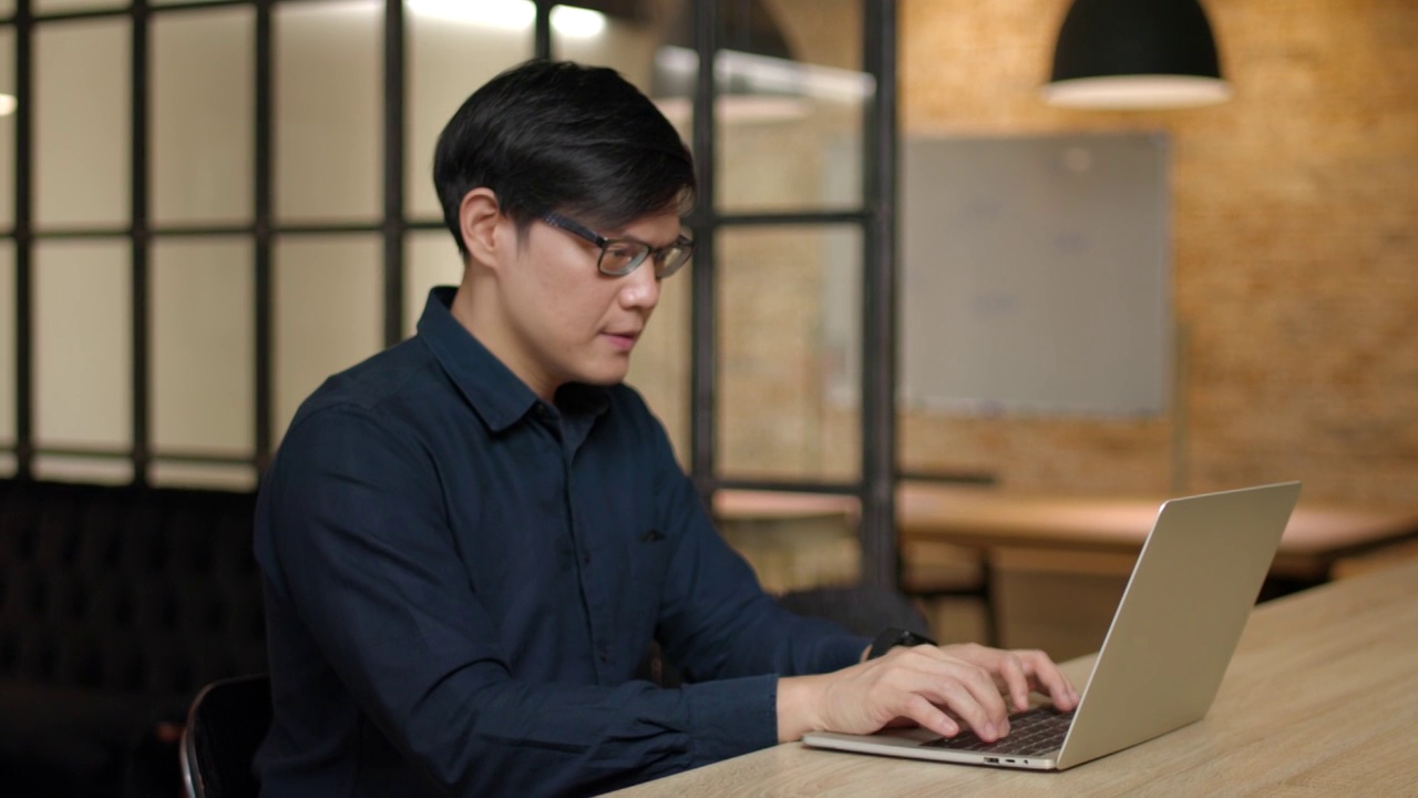 亚洲人在现代办公室使用笔记本电脑。视频下载