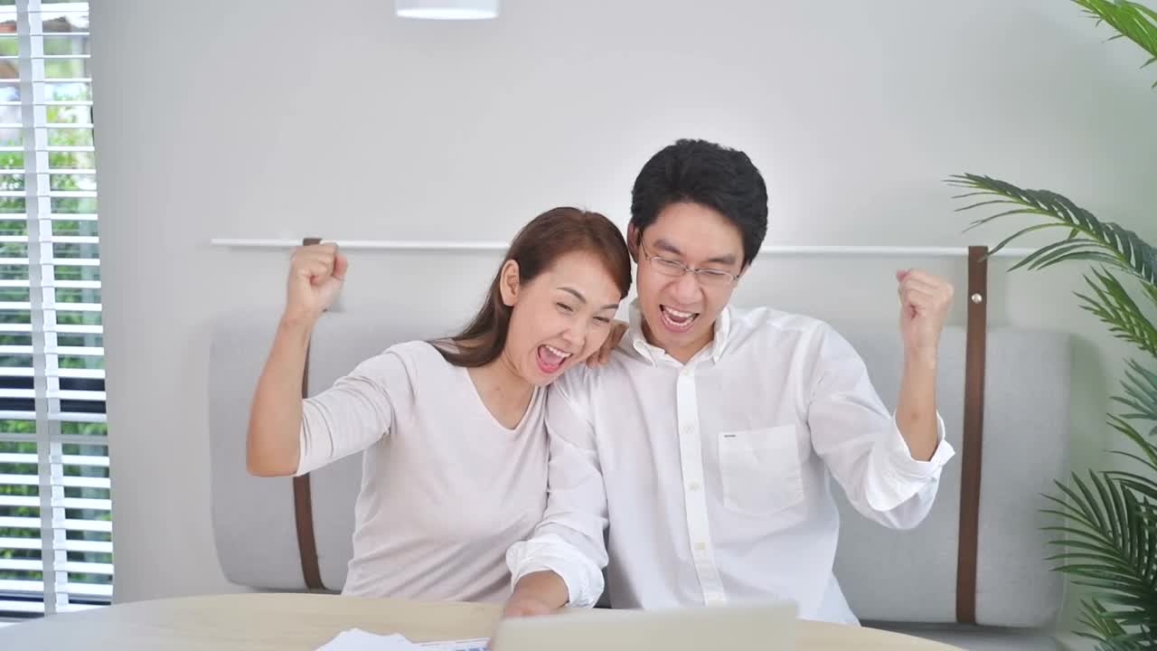 慢动作激动的亚洲夫妇使用笔记本电脑，获奖者视频素材