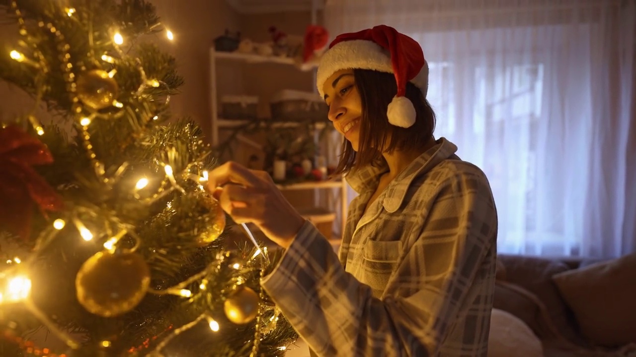 一个漂亮女人在家装饰圣诞树的慢镜头。在家中欢度圣诞，欢度新年的氛围理念视频素材