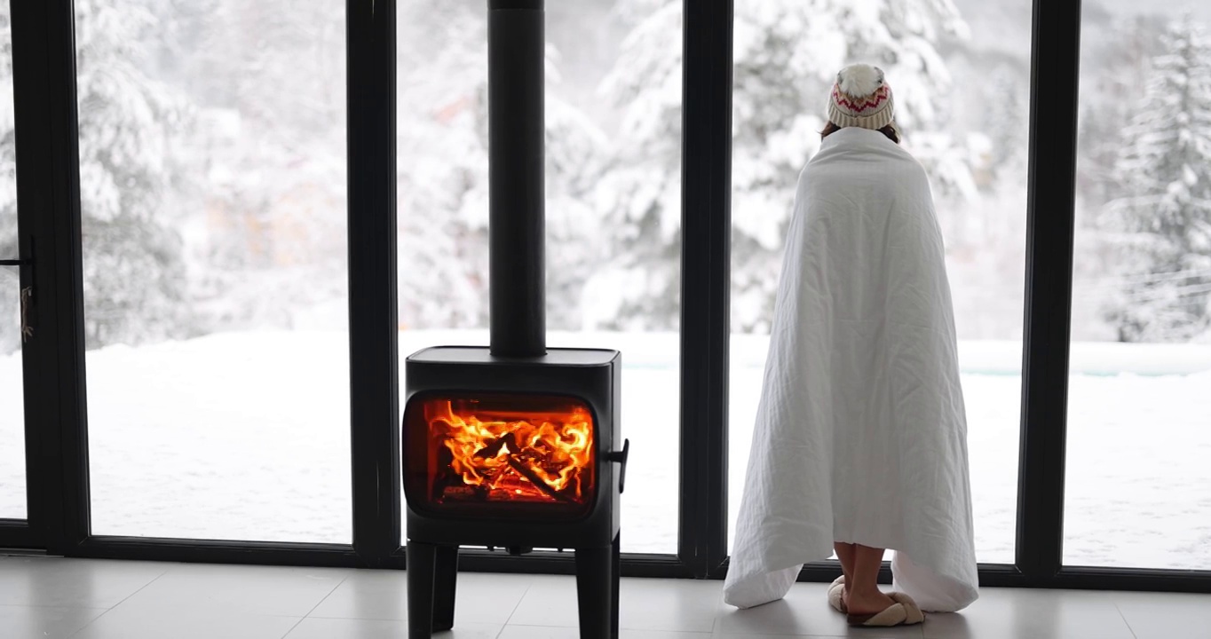 女人在家里燃烧的壁炉在冬天的自然视频下载