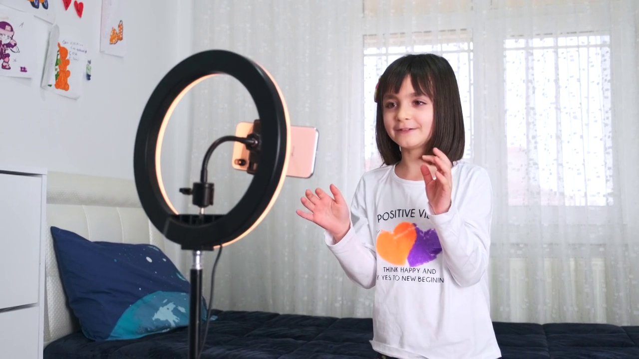侧视图画像的十几岁的女孩在家里拍摄视频和跳舞的相机设置在环灯，年轻的博主概念，复制空间视频素材
