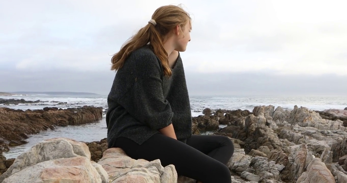 一个十几岁的女孩坐在岩石上，DeKelders，南非视频素材