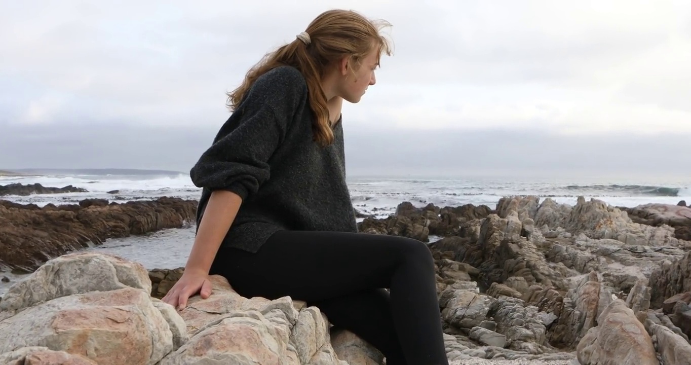 一个十几岁的女孩坐在岩石上，DeKelders，南非视频素材