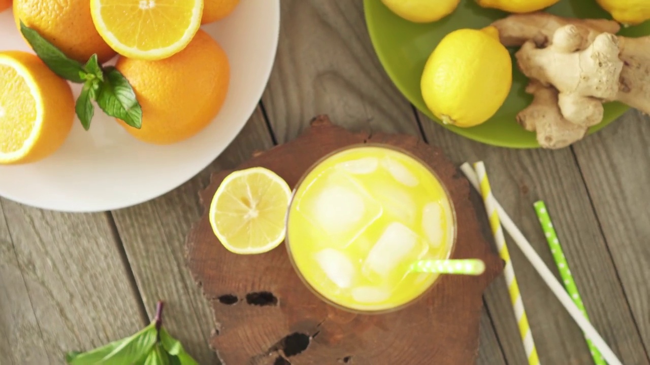 冰镇的柠檬水和冰块放在玻璃杯里。木桌上放着热带苏打水。盘子里装着橘子和薄荷视频下载
