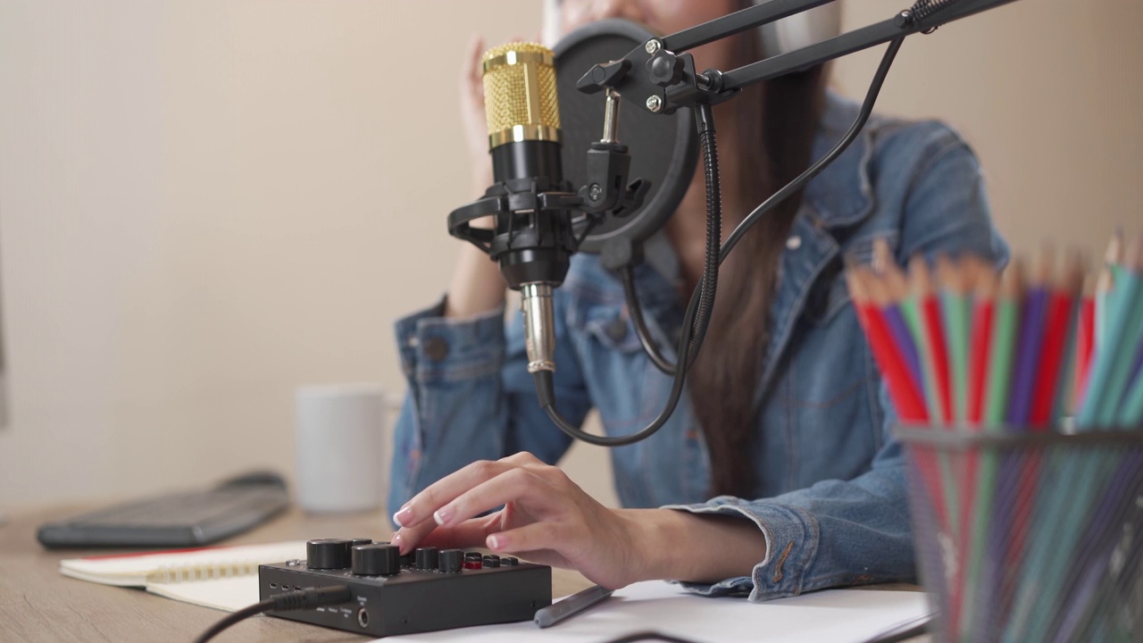 近距离的年轻亚洲妇女录制播客在她的笔记本电脑从家庭工作室。视频素材