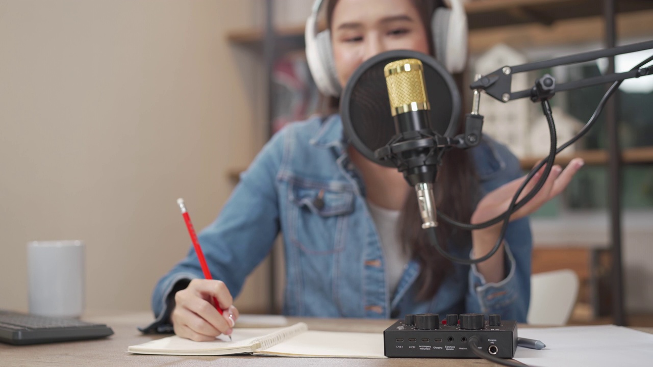 近距离的年轻亚洲妇女录制播客在她的笔记本电脑从家庭工作室。视频素材