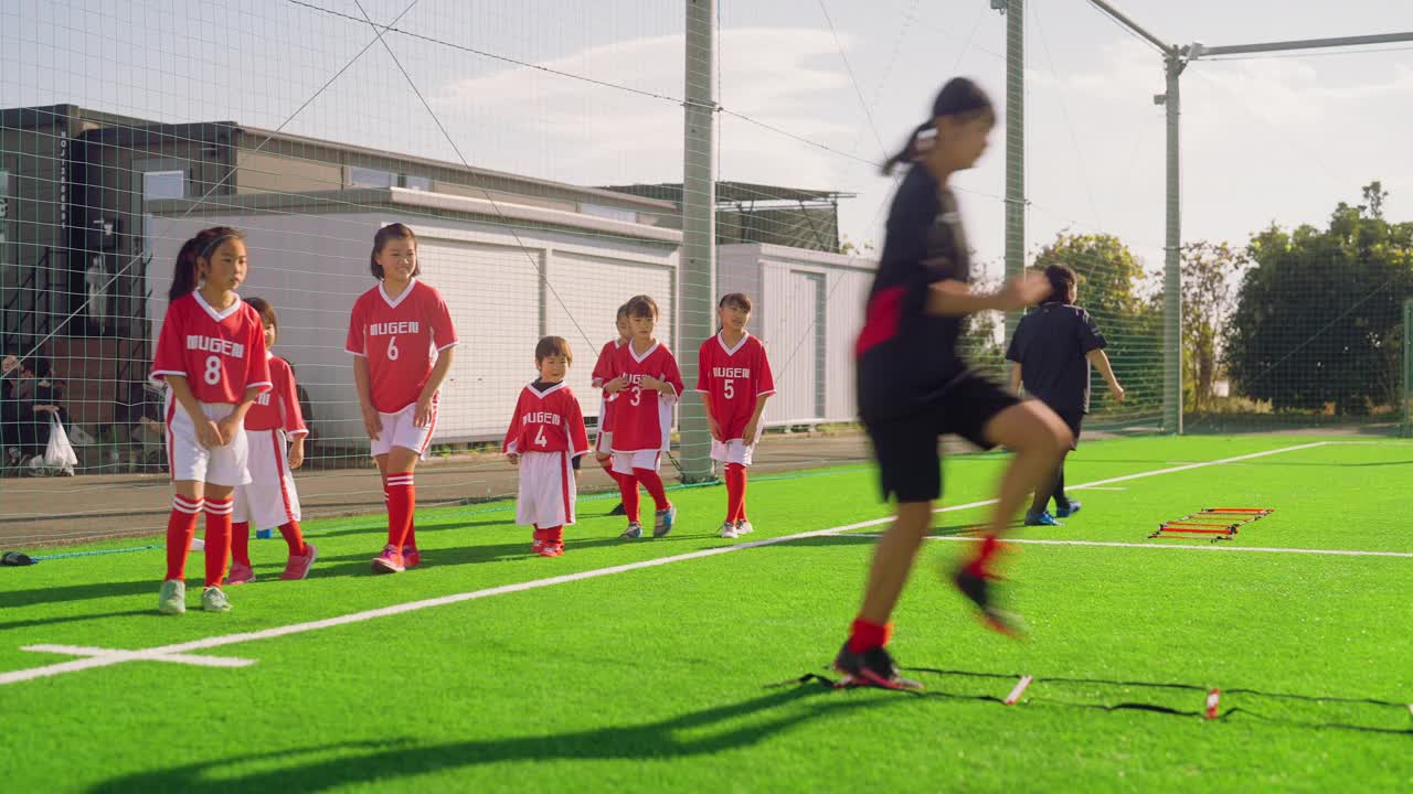 女子足球队或足球队队员在足球或足球场上进行敏捷性和快速跑训练视频下载