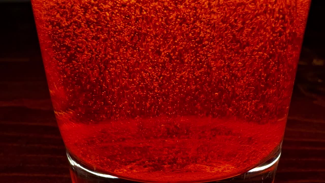 暗红色的液体在透明的饮水杯中冒泡视频素材