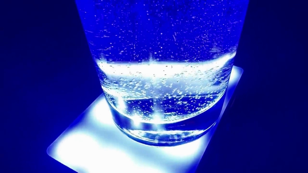 水在清澈的小玻璃杯里的蓝色水里起泡视频素材