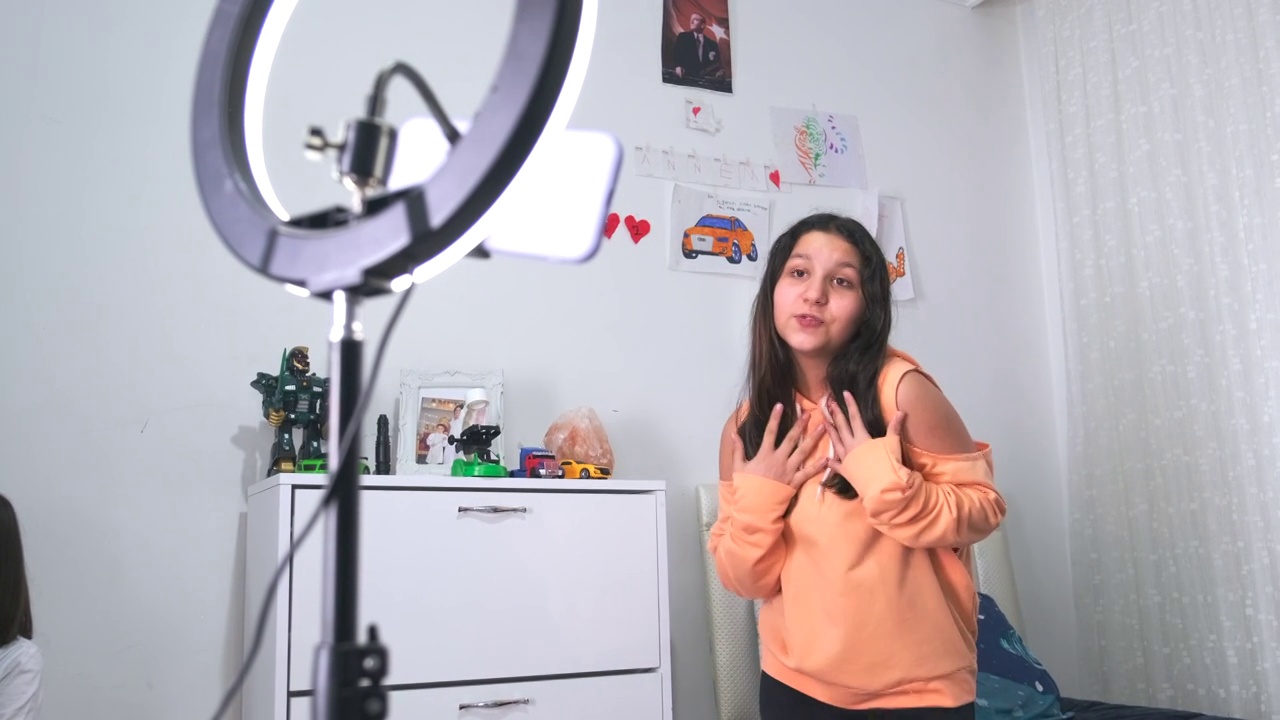 侧视图画像的十几岁的女孩在家里拍摄视频和跳舞的相机设置在环灯，年轻的博主概念，复制空间视频素材