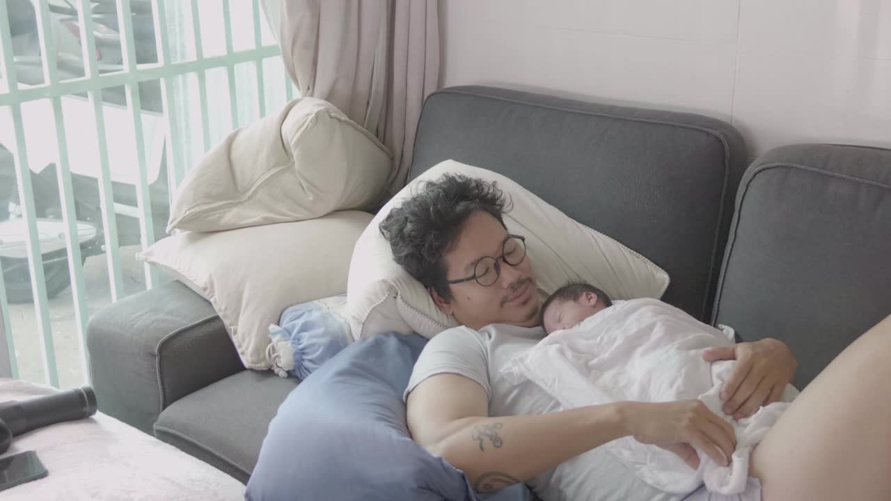 4k幸福疲惫的亚洲父亲和儿子睡在沙发上早上。视频素材