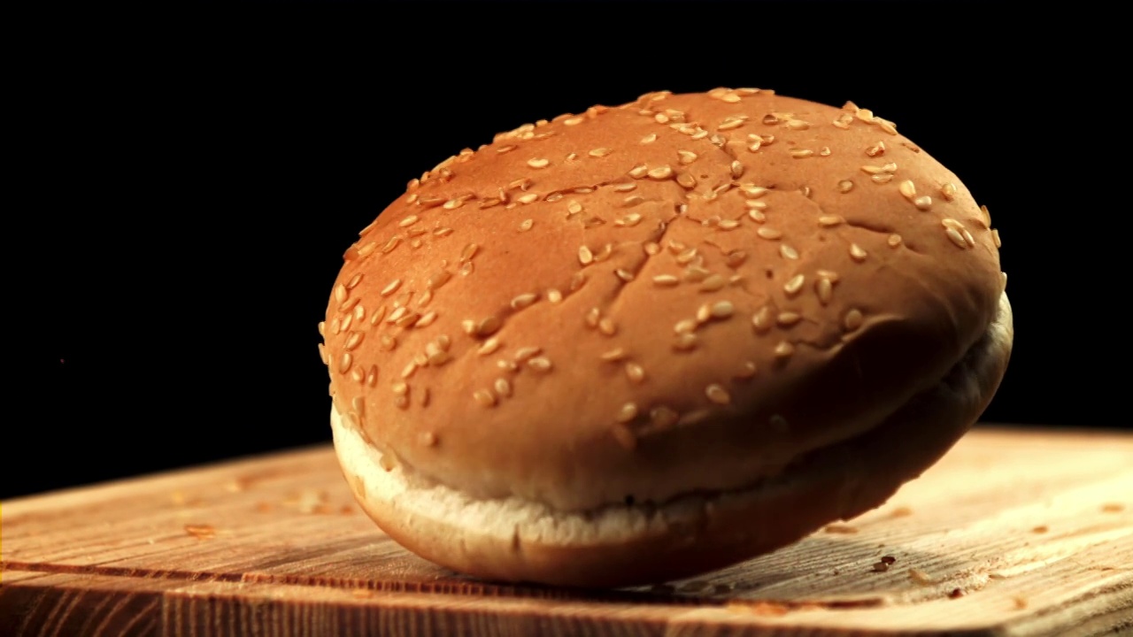 一个汉堡面包掉在切菜板上。拍摄的是慢动作每秒1000帧。视频下载