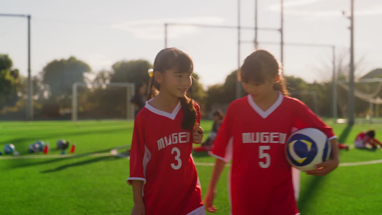 两名女足或足球队队员抱着足球，边走边聊视频素材